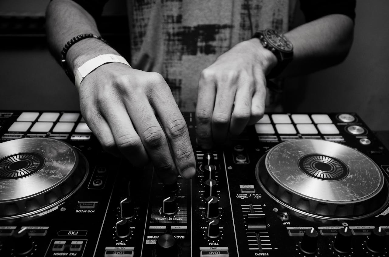 Close-up of a DJs hands adjusting controls on a mixer in monochrome.